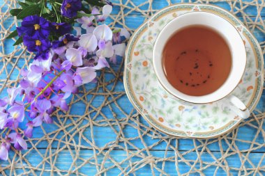 Bir fincan çay ahşap bir mavi masa üzerinde renkli fi bir buket