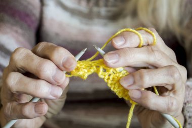Kadınların elleri tutun örgü iğneleri ve kravat için sarı bir iplik 