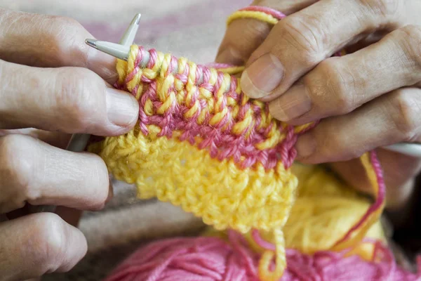 Women's  hands hold knitting needles and a yellow thread to tie Stock Picture