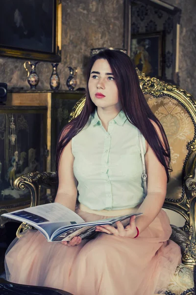 Ganska ung kvinna med mörkt långt hår och blå ögon läsa bok Royaltyfria Stockbilder