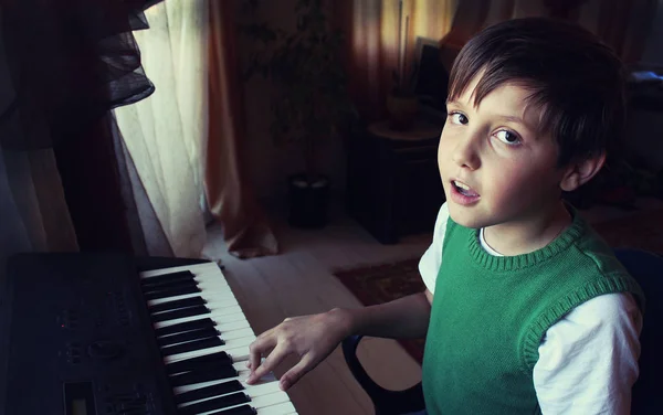 绿色 t 恤的男孩弹钢琴和微笑 — 图库照片