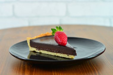 Siyah tabakta çilek ile Çikolatalı tart.