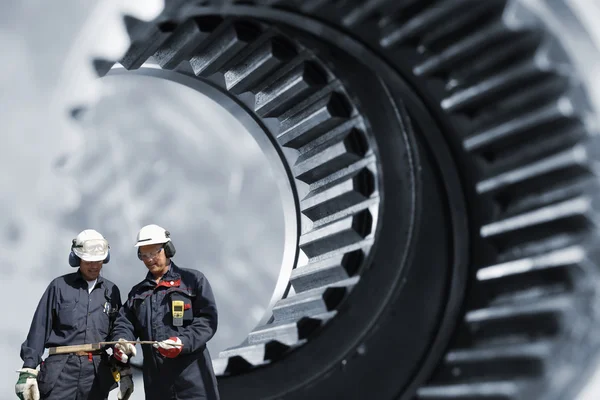 Twee mechnics en giant machinedelen Rechtenvrije Stockafbeeldingen