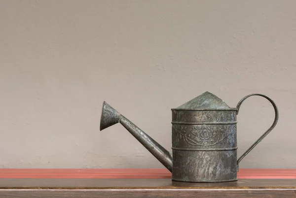 Vintage style watering can on shelf with brown wall background — Stock Photo, Image