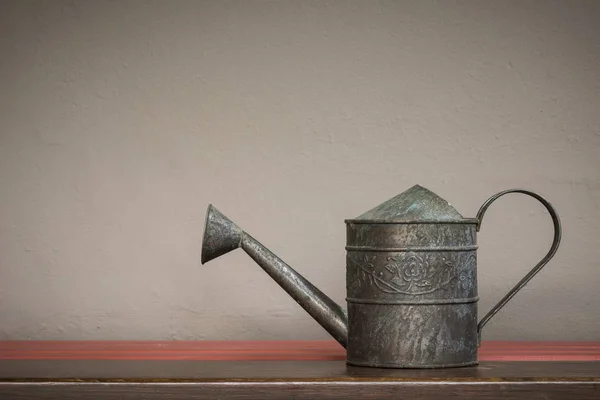 Vintage style watering can on shelf with brown wall background — Stock Photo, Image