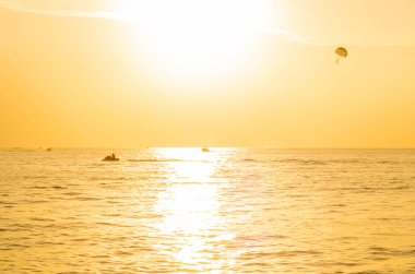 Günbatımında Phuket Beach, Tayland 'da paraşütle atlayan turistler