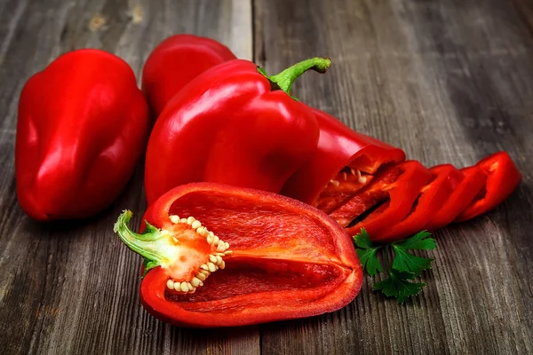 Fatias de pimentão vermelho em um fundo de madeira — Fotografia de Stock