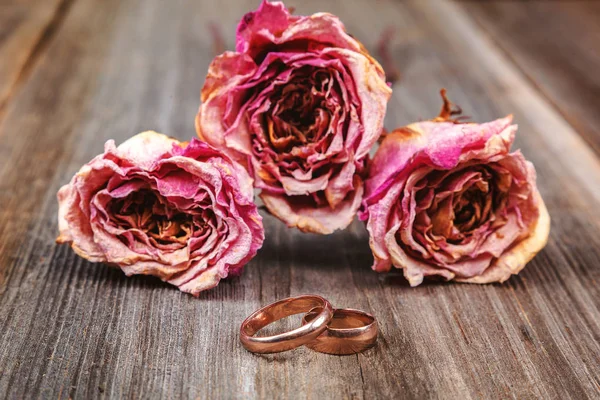 Fedi nuziali e rose fiori secchi su sfondo di legno — Foto Stock