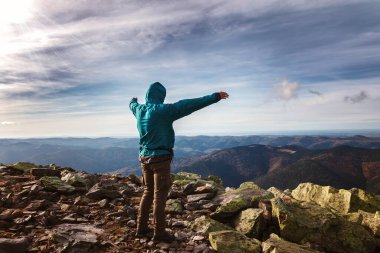 Genç adam bir dağın tepesinde duruyor..