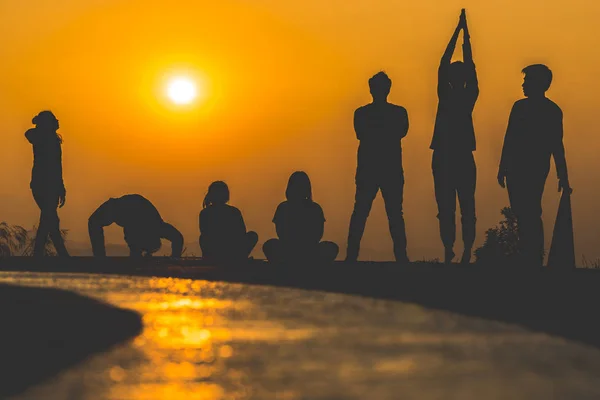 Silhouette di persone che praticano yoga sulla montagna al tramonto — Foto Stock