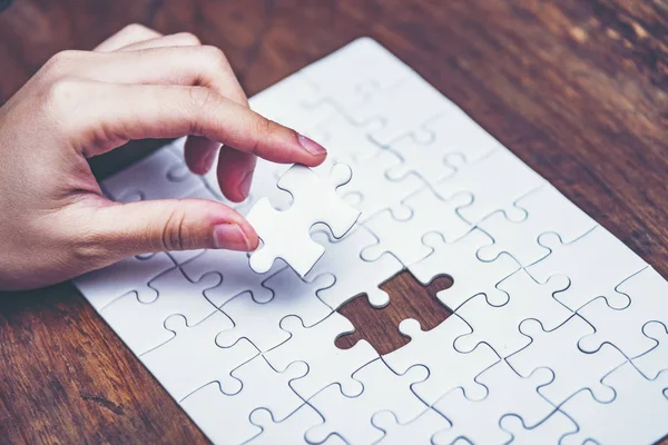 Business solutions, success and strategy concept. Businessman hand connecting jigsaw puzzle.