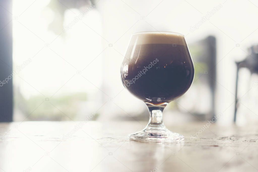 frothy sparkling nitro cold brew ready to be served at coffee shop bar environment background. coffee machine wooden table vintage