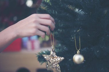 women hand setting decorations and gift boxes on Christmas tree