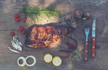 Baharatlı, ızgara pirzola. Barbekü, acı biber ve taze domatesle servis edilir. Eski bir ahşap kesim tahtasının üzerinde.