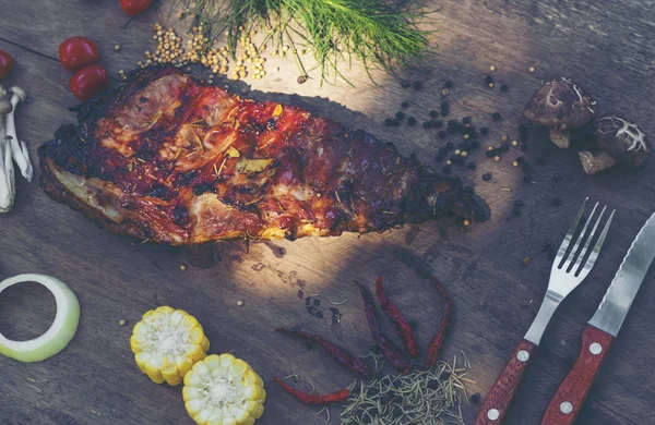 Baharatlı, ızgara pirzola. Barbekü, acı biber ve taze domatesle servis edilir. Eski bir ahşap kesim tahtasının üzerinde.