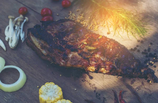 Baharatlı, ızgara pirzola. Barbekü, acı biber ve taze domatesle servis edilir. Eski bir ahşap kesim tahtasının üzerinde.