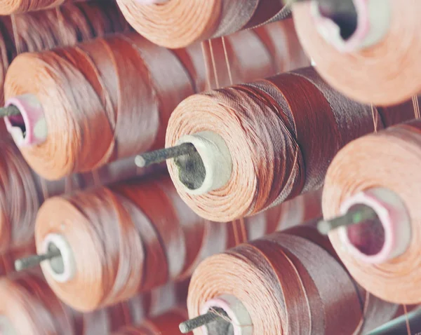 Brown yarn cone mounted in a fabrics factory.