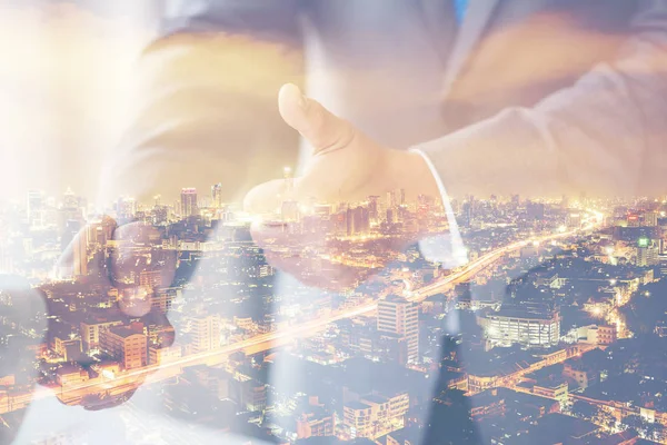 Double Exposure bir işadamı el sıkışmanın arka planda şehir gece hayatı bulanık. Bir anlaşma yeşil enerji kavramı.
