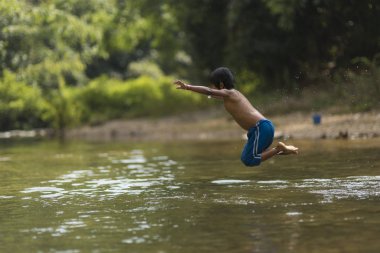 Mandalay, Myanmar - Circa, September 2015: Burmar teenager jumping in a river.