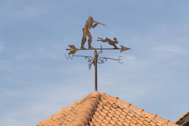 Weather vane showing direction of wind against clear blue sky. Metal weather vane with hunter silhouette