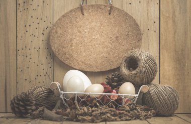 pine cones, ropes and eggs in a basket on a wooden background.