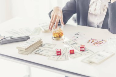 businesswoman with a glass of whiskey, money and dice cubes the table