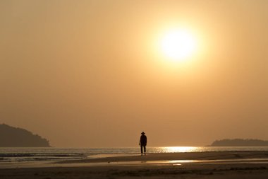 gün batımında deniz kenarında yalnız adam