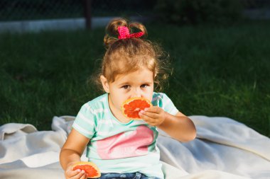 Küçük kız bir dilim taze greyfurt tutar