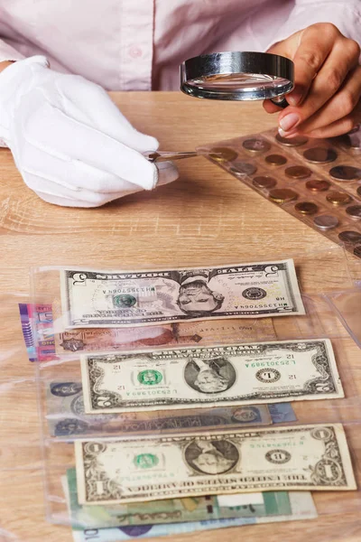 Kobieta patrzy na monety dolara przez lupę — Zdjęcie stockowe