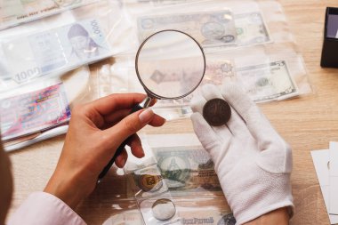 Kadın parayı büyüteç ile görünüyor.
