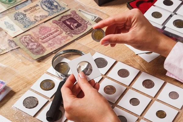 Woman looks at the old coin — Stock Photo, Image