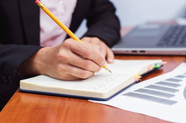 Bir kalem, not defteri ve birkaç grafikler ile el