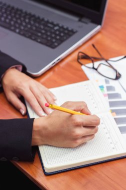 Bir kalem, not defteri ve birkaç grafikler ile el