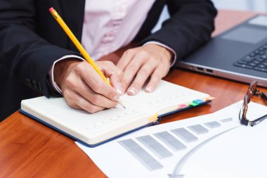 Bir kalem, not defteri ve birkaç grafikler ile el