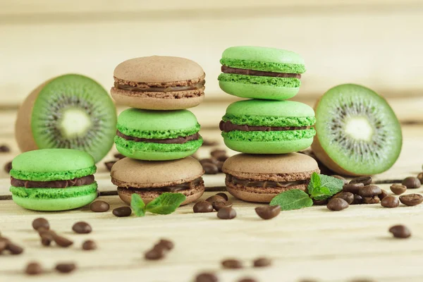 Green and brown french macarons with kiwi, coffee beans and mints decorations — Stock Photo, Image