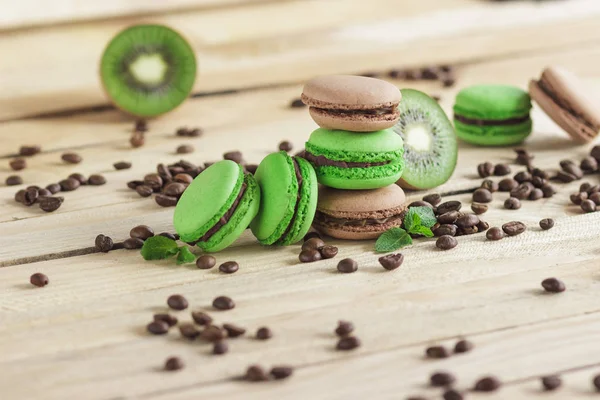 Green and brown french macarons with kiwi, coffee beans and mints decorations — Stock Photo, Image