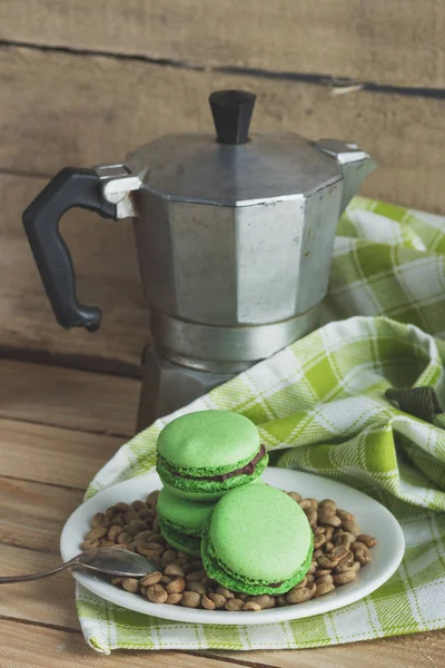 緑のコーヒー豆、コーヒー ポット、格子縞のナプキンを板緑マカロン — ストック写真