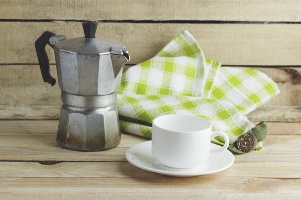 Kop op de schotel, koffie pot en plaid servet, houten achtergrond — Stockfoto