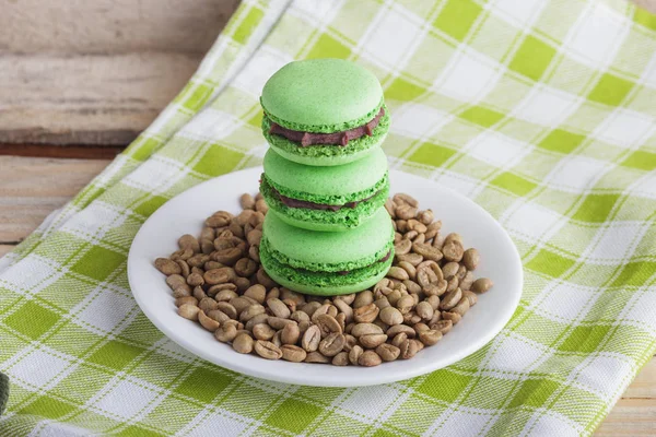 Green macarons on the plate with green coffee beans — Stock Photo, Image