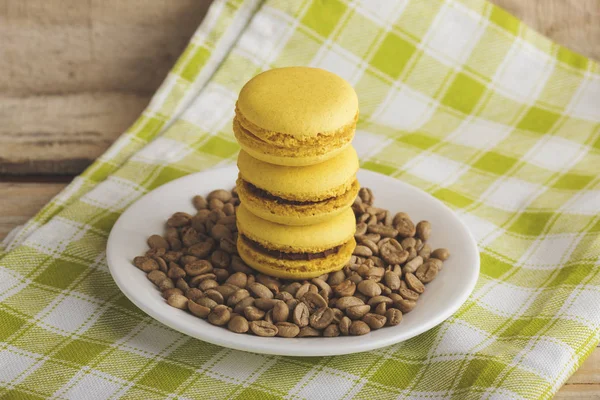 Yellow macarons on the plate with green coffee beans — Stock Photo, Image