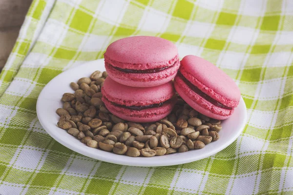 Pink macarons on the plate with green coffee beans — Stock Photo, Image