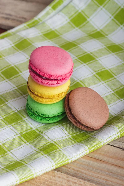 Brown, yellow, green and pink macarons on the plaid napkin — Stock Photo, Image