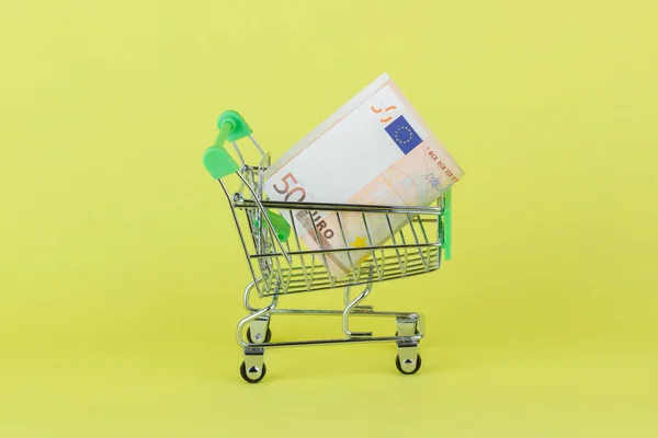 Vijftig euro in de winkelstraat pushcart, gele achtergrond — Stockfoto