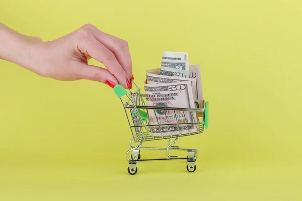 美国美元在购物手推车，黄色背景 — 图库照片
