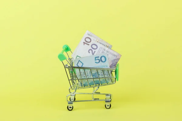 Poolse zloty op de winkelstraat pushcart, gele achtergrond — Stockfoto