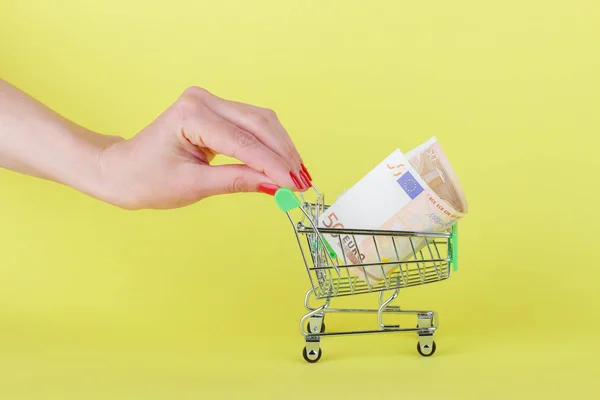 Fünfzig Euro im Einkaufswagen, gelber Hintergrund — Stockfoto