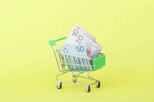 Poolse zloty op de winkelstraat pushcart, gele achtergrond — Stockfoto