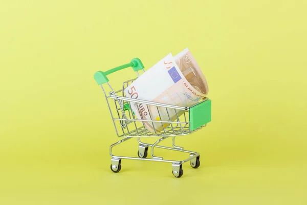 Vijftig euro in de winkelstraat pushcart, gele achtergrond — Stockfoto