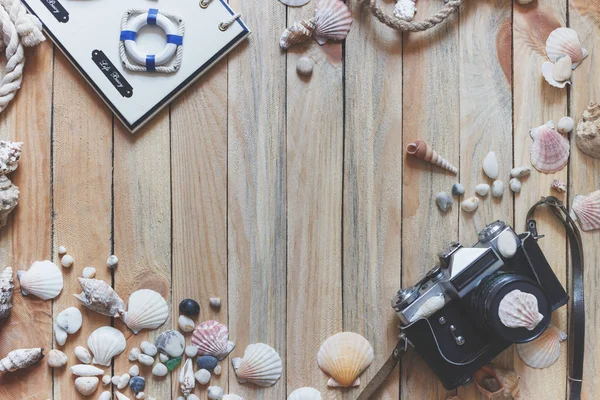 Photo camera and marine decorations on the wooden background