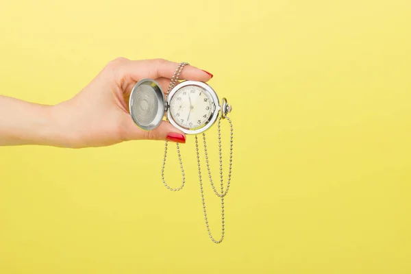 Relógio de bolso na mão da mulher, fundo amarelo — Fotografia de Stock
